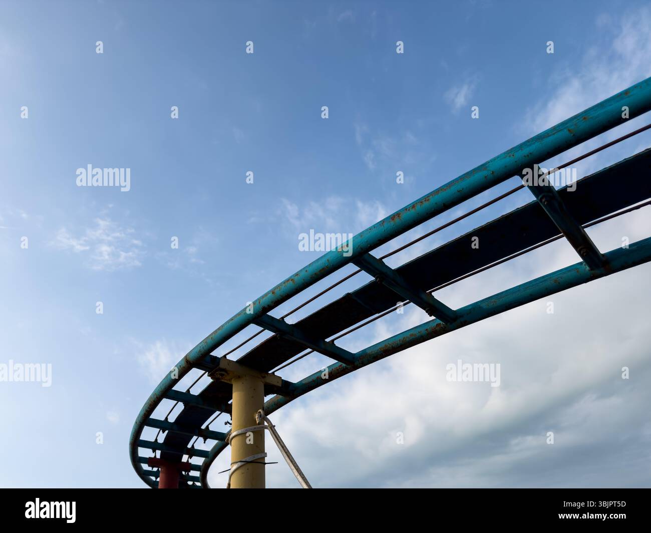 Pista a rulli in metallo curvo contro il cielo blu dinamico, struttura astratta per esterni con senso di movimento e libertà. Niente persone. Foto Stock