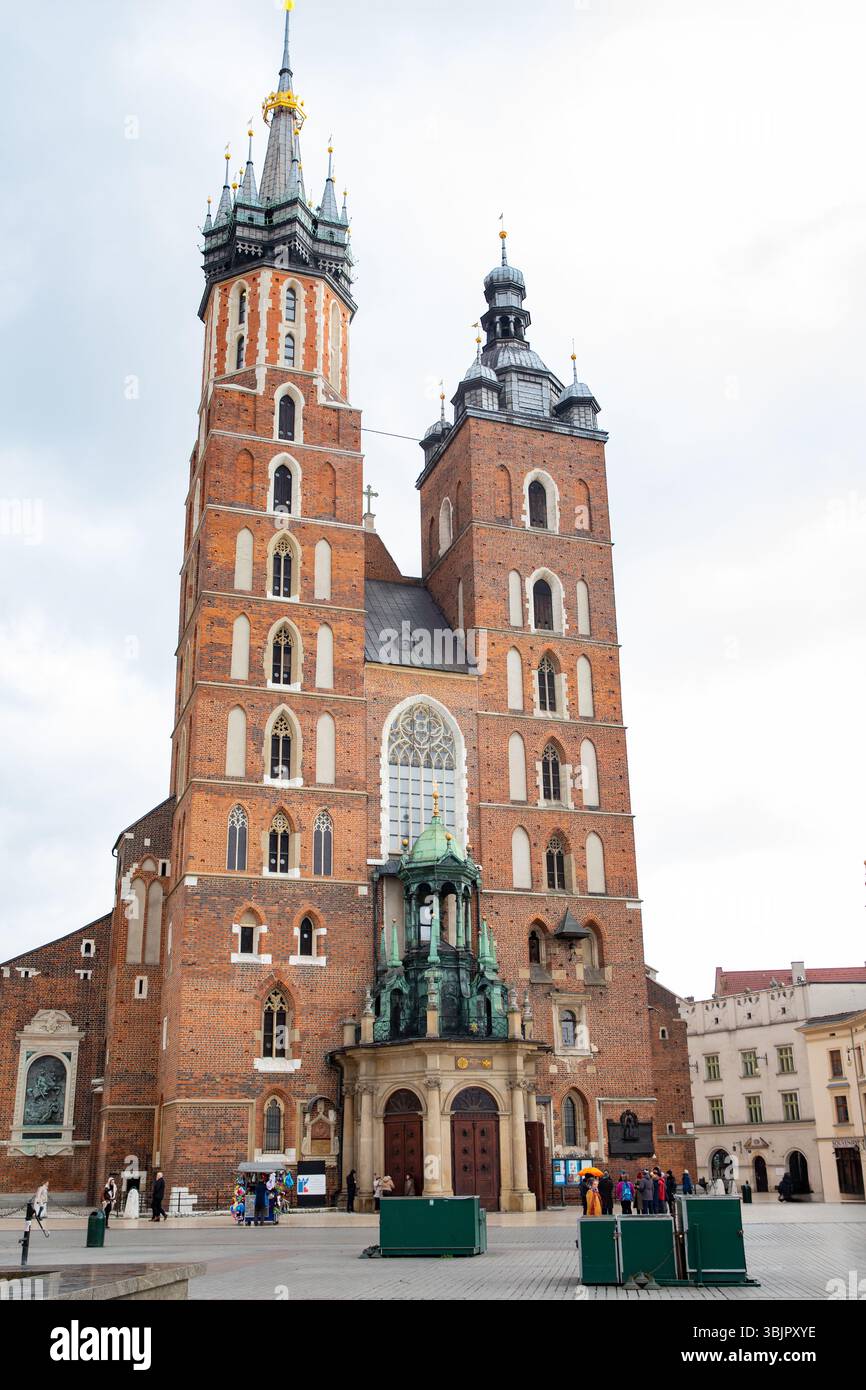 La chiesa storica presenta torri gemelle e dettagliate opere in mattoni, circondate da visitatori e paesaggi urbani, che mettono in risalto la bellezza architettonica e culturale Foto Stock