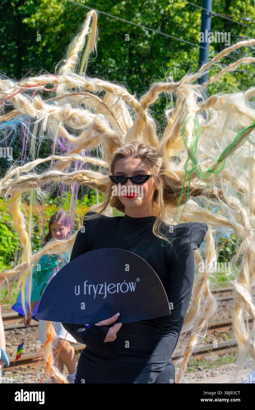 Un partecipante alla Pride Parade che indossa occhiali da sole e un acconciatore a punta che tiene un fan "u fryzjerów" alla Parata del Pride di Varsavia a Varsavia, Voivodato della Masovia, Foto Stock