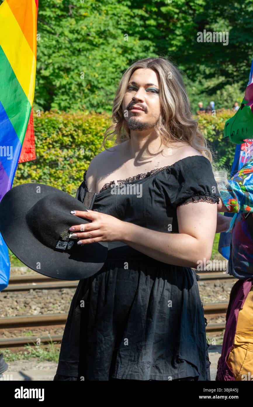 Un partecipante alla parata che indossa un vestito nero e tiene in mano un cappello e una bandiera arcobaleno alla parata dell'orgoglio di Varsavia, Varsavia, Voivodato della Masovia, Polonia, 2 giugno Foto Stock