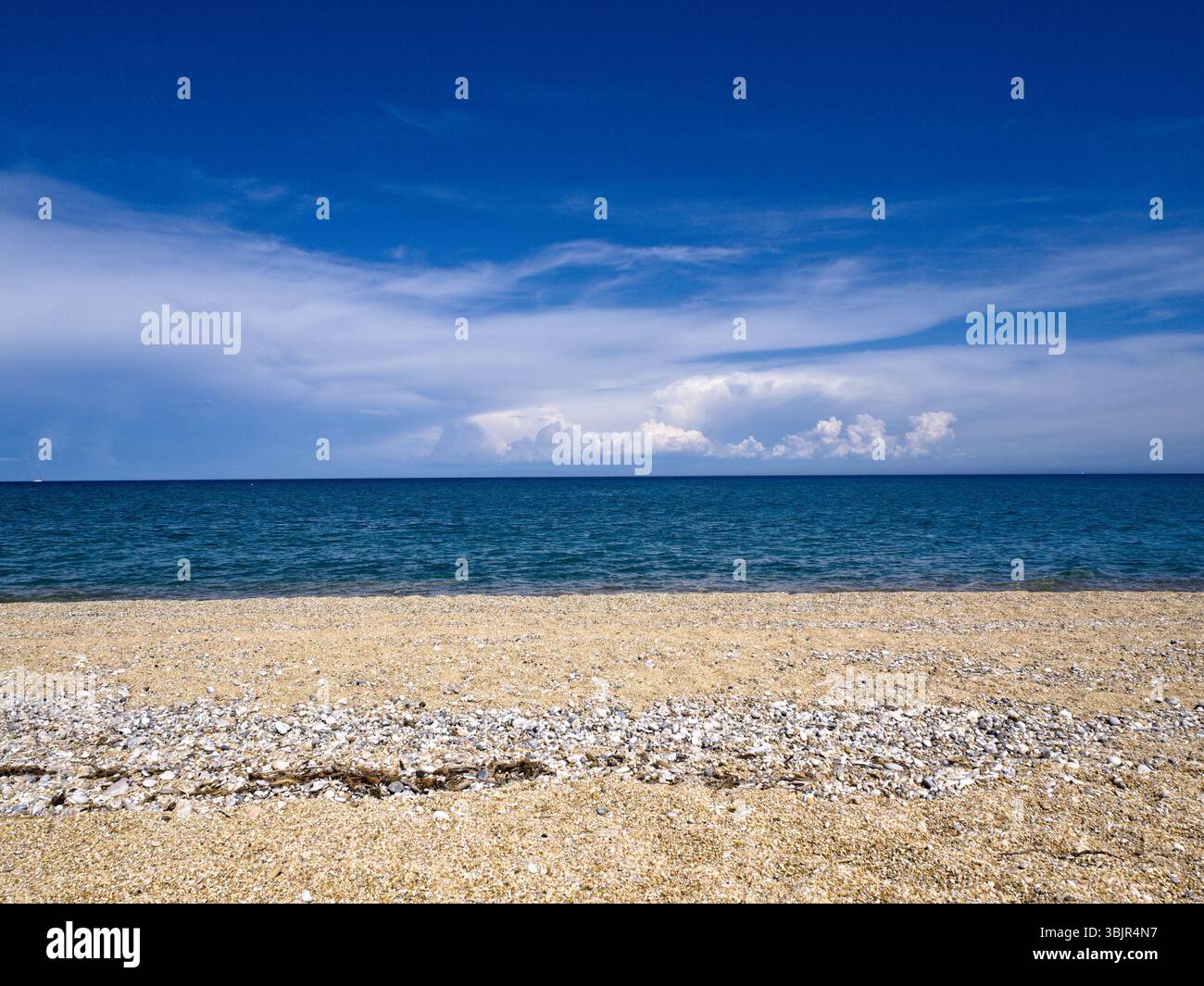 Layout orizzontale di sabbia, mare e cielo in terzi naturali, ideale per sovrapposizione di testo e uso del branding. Foto Stock