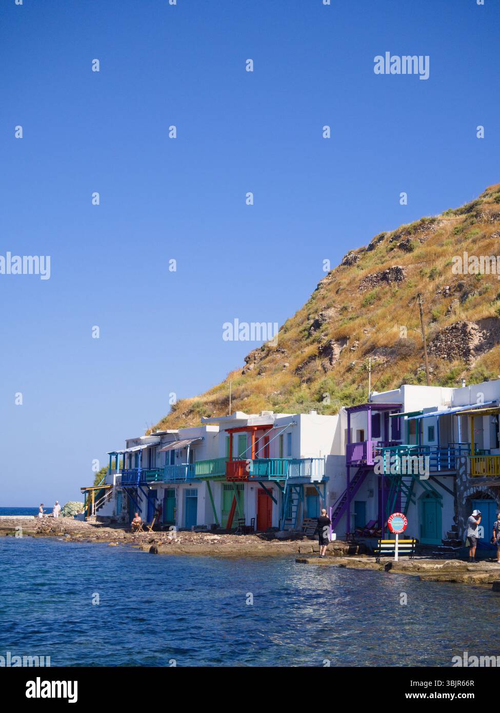 Milos, Grecia - i turisti camminano accanto alle colorate case costiere del villaggio di Klima, un tradizionale insediamento delle Cicladi sul mare. Solo per uso editoriale. Foto Stock