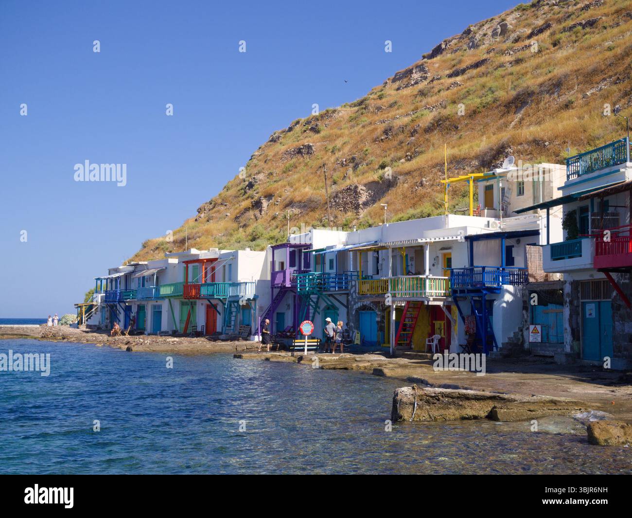 Milos, Grecia: Gli abitanti del posto e i visitatori si godono un pomeriggio di sole al mare nel villaggio di Klima. La scena mostra case colorate sul mare e acque calme. Foto Stock