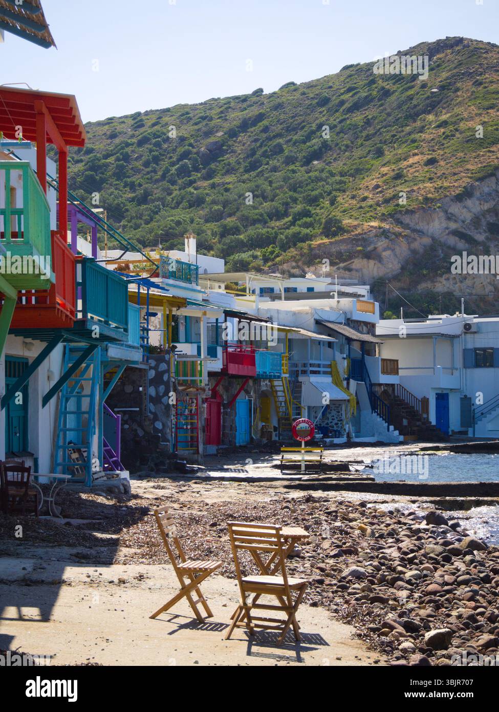 Facciate illuminate dal sole delle tradizionali case greche nel villaggio costiero di Klima sull'isola di Milos. Atmosfera mediterranea con facciate dipinte di bianco. Foto Stock