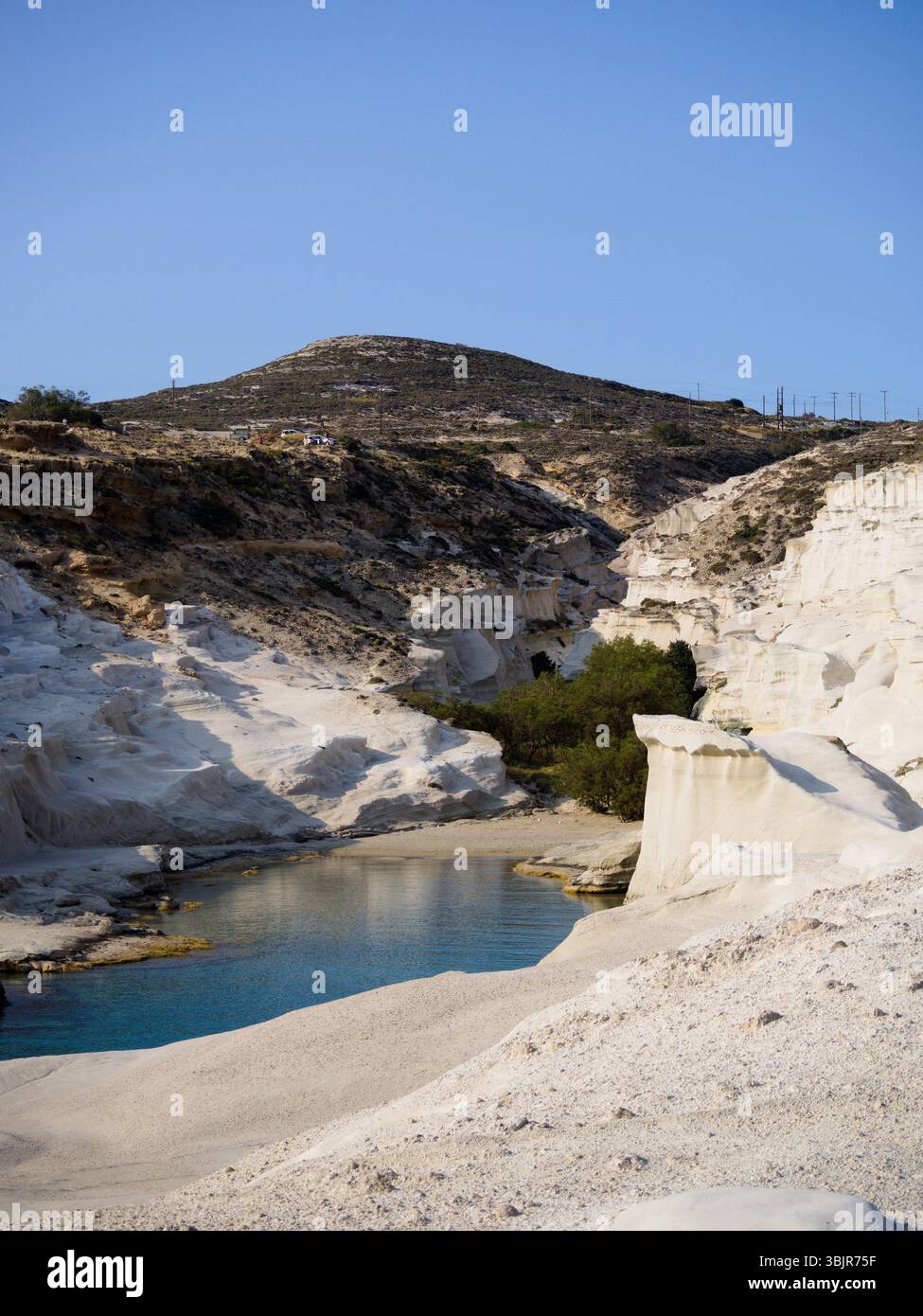 Primo piano costiero di Sarakiniko, l'isola di Milos, che mostra bianche scogliere vulcaniche e il limpido Mar Egeo sotto la luce del sole Foto Stock