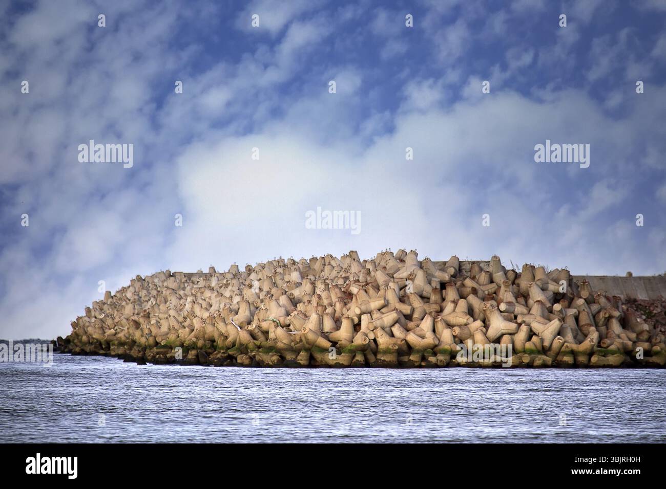 La diga intorno agli impianti del porto marittimo è realizzata in tetrapodi di cemento (protezione contro le onde mobili), frangiflutti di macerie Foto Stock