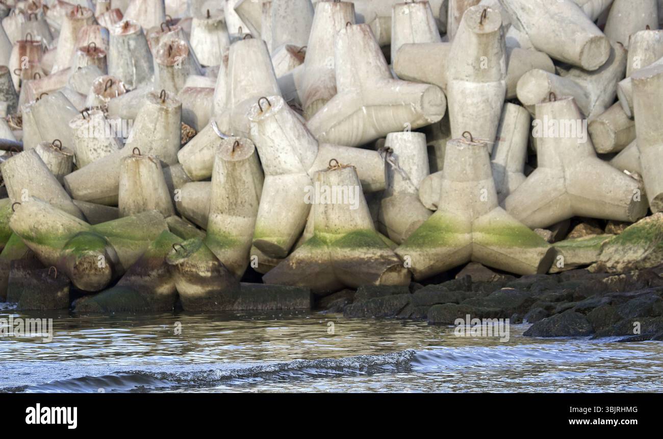 La diga intorno agli impianti del porto marittimo è realizzata in tetrapodi di cemento (protezione contro le onde mobili), frangiflutti di macerie Foto Stock