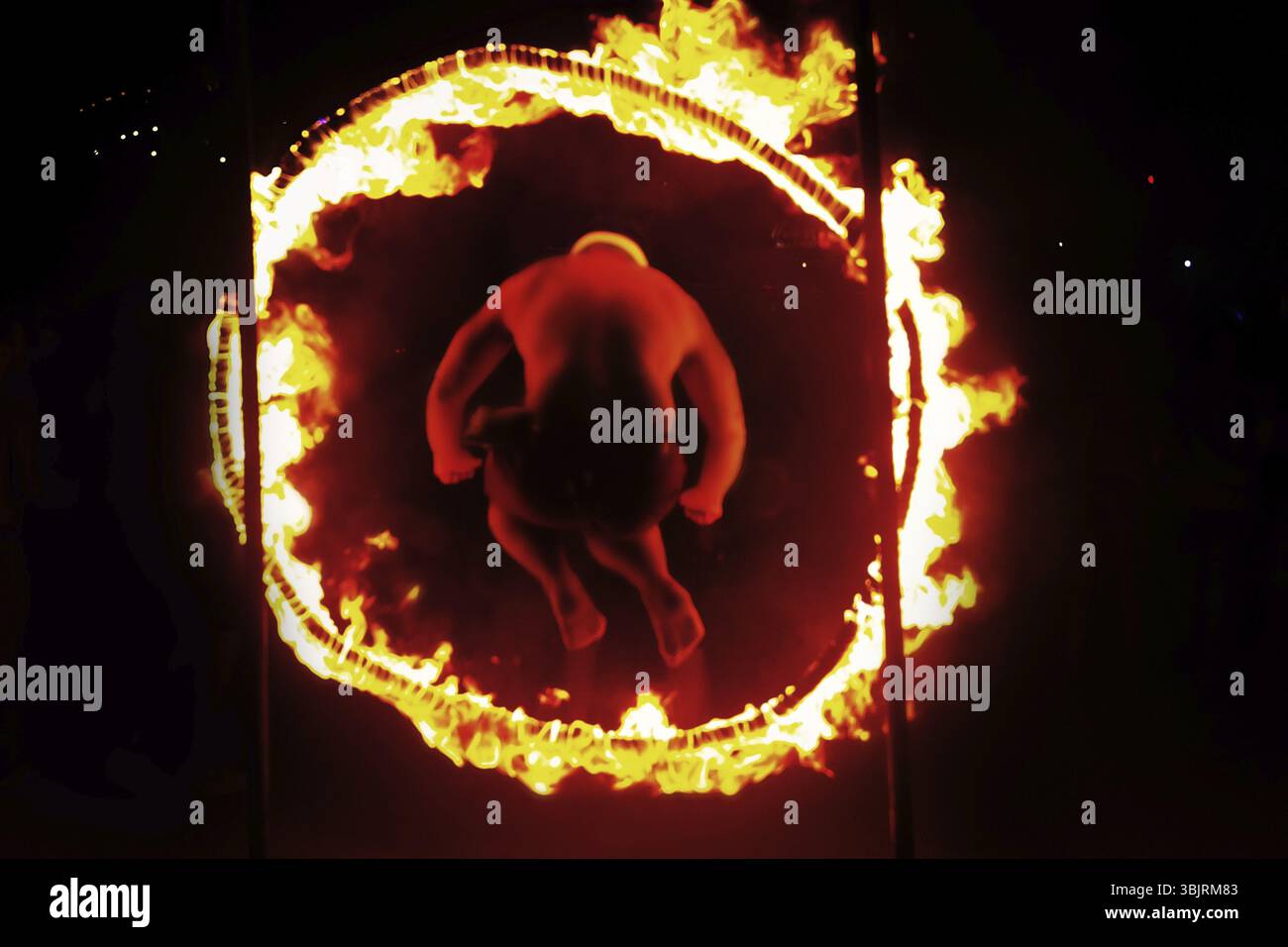 Un uomo passa in un cerchio di fuoco. Silhouette anonima sfocata irriconoscibile di notte Foto Stock