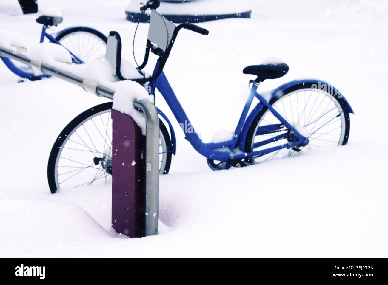 Inaspettata nevicata, disastri naturali e rimozione della neve. City bike nel parcheggio coperto da neve completamente, la fine della stagione ciclistica e il Foto Stock