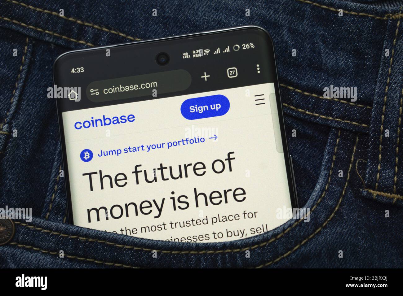 Dhaka, Bangladesh- 15 giugno 2025: Uno smartphone con l'interfaccia Web coinbase.com sbuca fuori da una tasca in denim Foto Stock