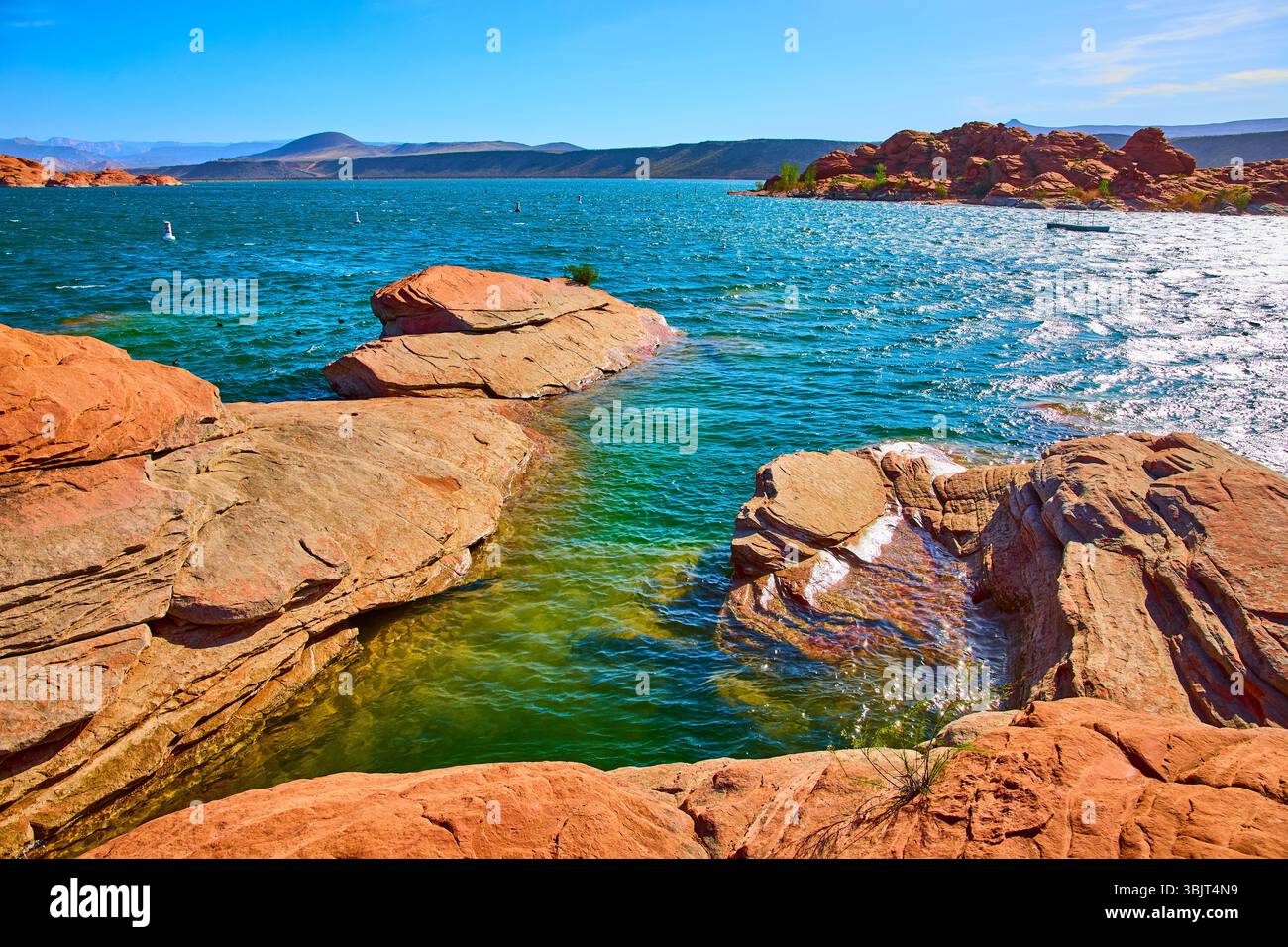Red Sandstone e Blue Lake Water con Distant Hills Low Angle Lake Edge Foto Stock