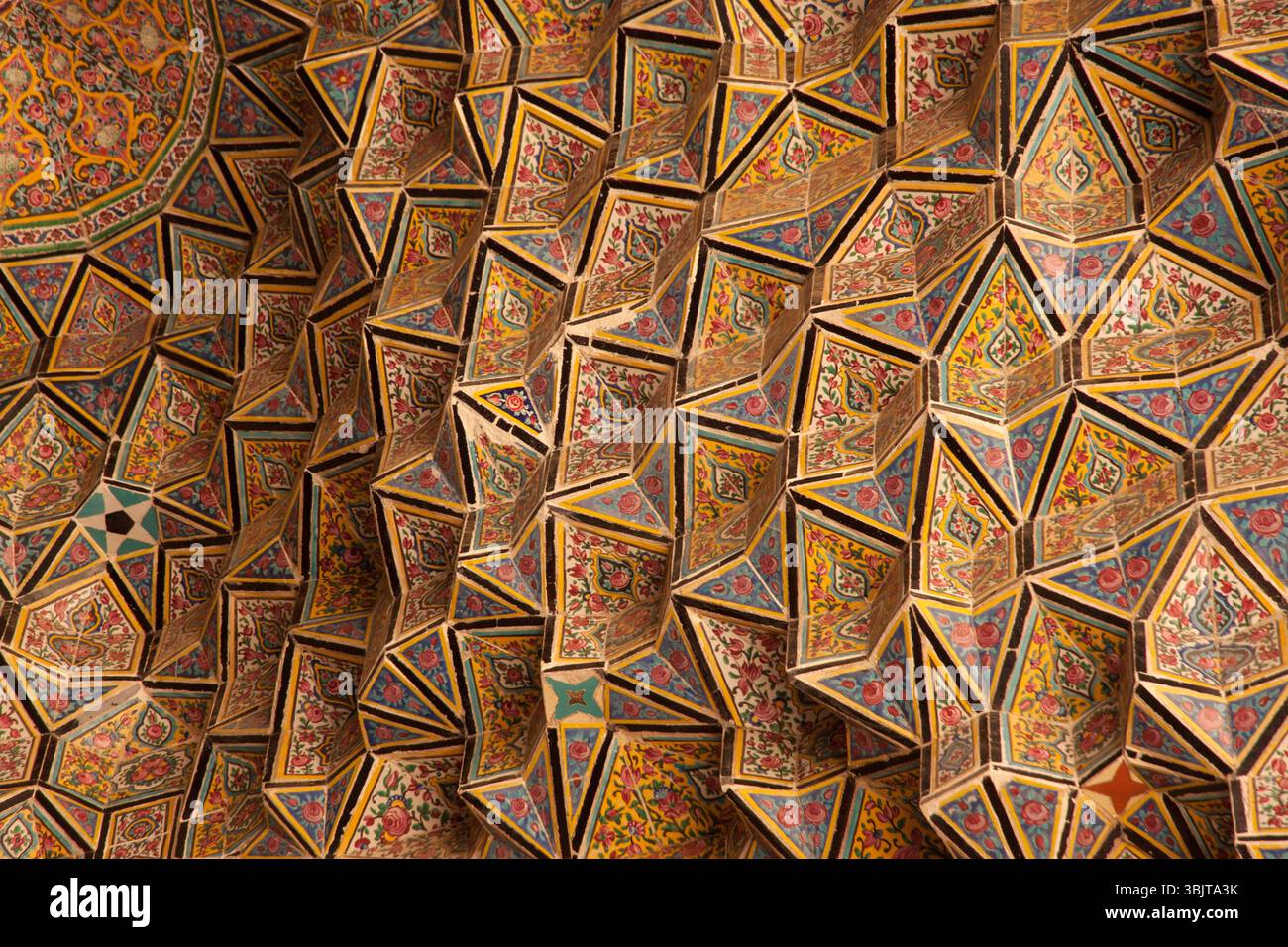 Soffitto geometrico ornato di una moschea a Shiraz, Iran, che mostra l'artigianato tradizionale persiano, colori vivaci e design islamico. Foto Stock
