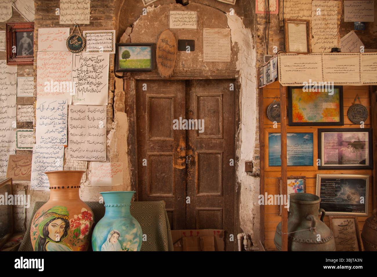 Colorata poesia persiana scritta a mano e decorazioni tradizionali su un vecchio muro a Shiraz, Iran, che riflette la ricca cultura letteraria e artistica. Foto Stock