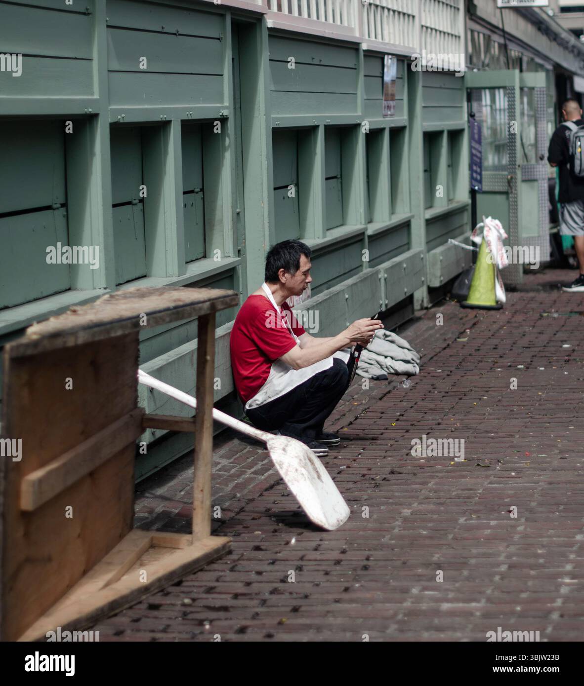 Un pescatore di Seattle si prende una pausa sperando di trovare un po' di solitudine nelle vivaci strade del centro di Seattle. Foto Stock