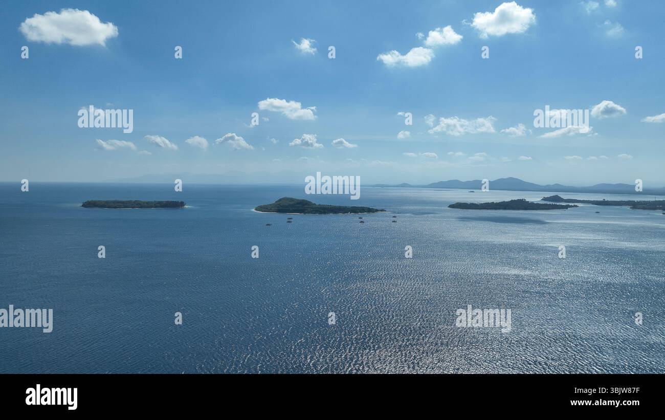 Le tradizionali piattaforme di pesca di bambù galleggiano in mare aperto con verdi montagne sullo sfondo. Questa scena unica cattura lo spirito dell'isola Foto Stock