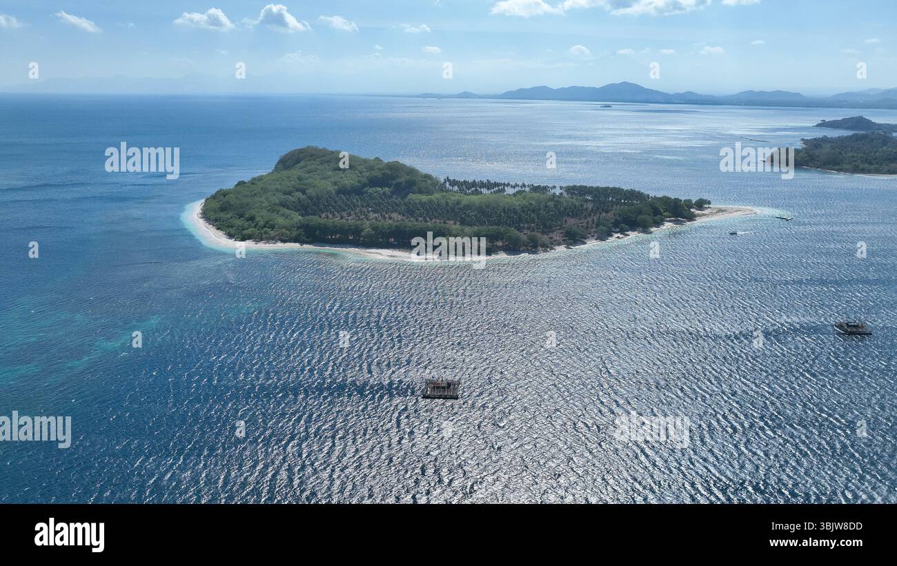 Scopri il fascino tranquillo dell'isola di Tangkong, dove la vegetazione lussureggiante incontra le acque turchesi e le tradizionali piattaforme di pesca di bambù galleggiano dolcemente Foto Stock