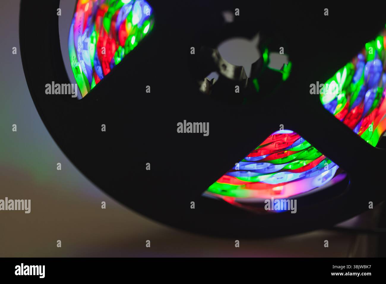 Una bobina con vivaci luci LED multicolore che si illuminano in modo vivace su uno sfondo scuro, mostrando la loro essenza colorata e tecnologica in un mesmeriz Foto Stock