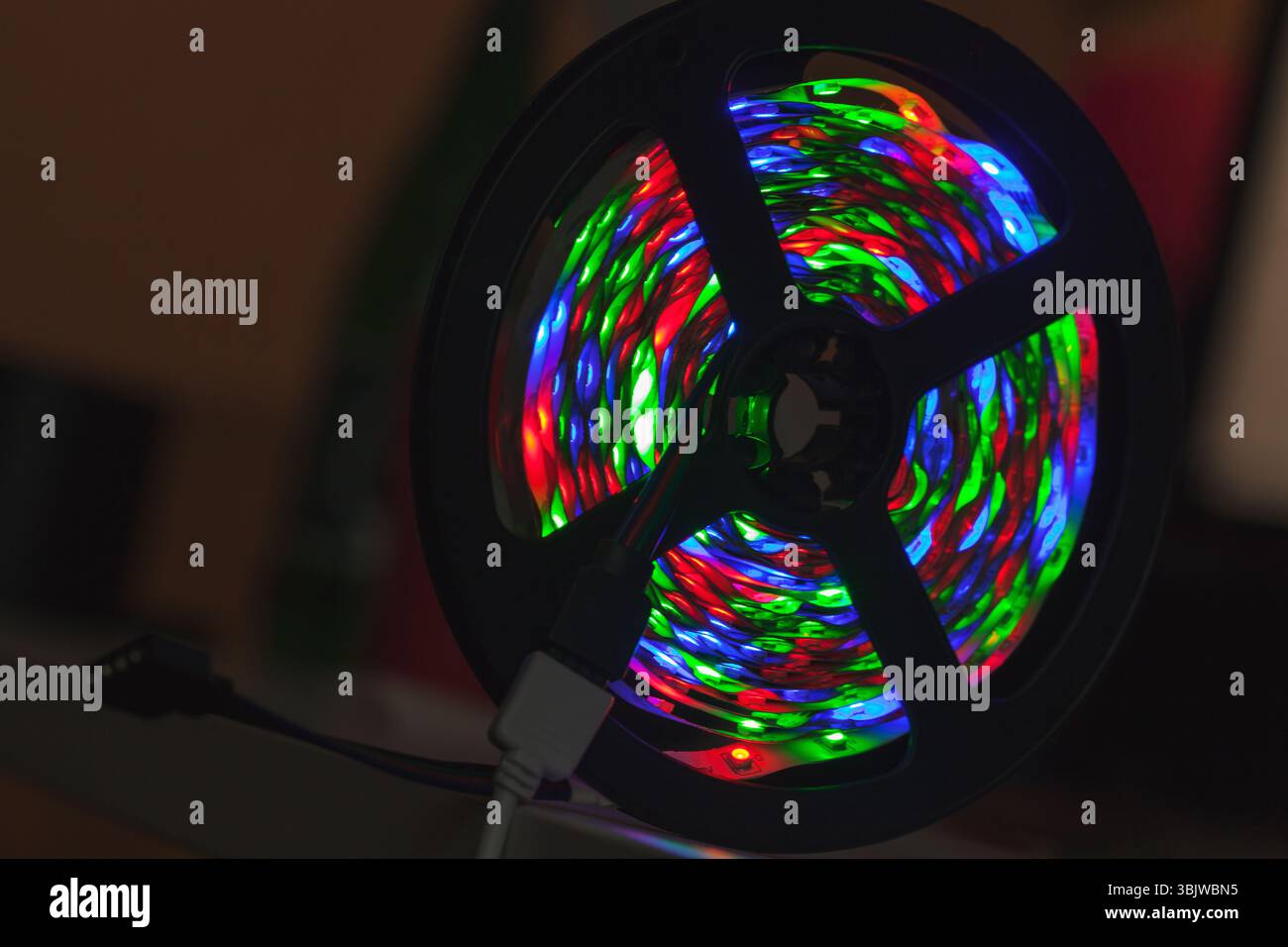 Un'immagine sorprendente di una bobina con vivaci luci LED multicolore che si illuminano in modo vivace su uno sfondo scuro, mettendo in risalto la loro tecnologia e colorata Foto Stock