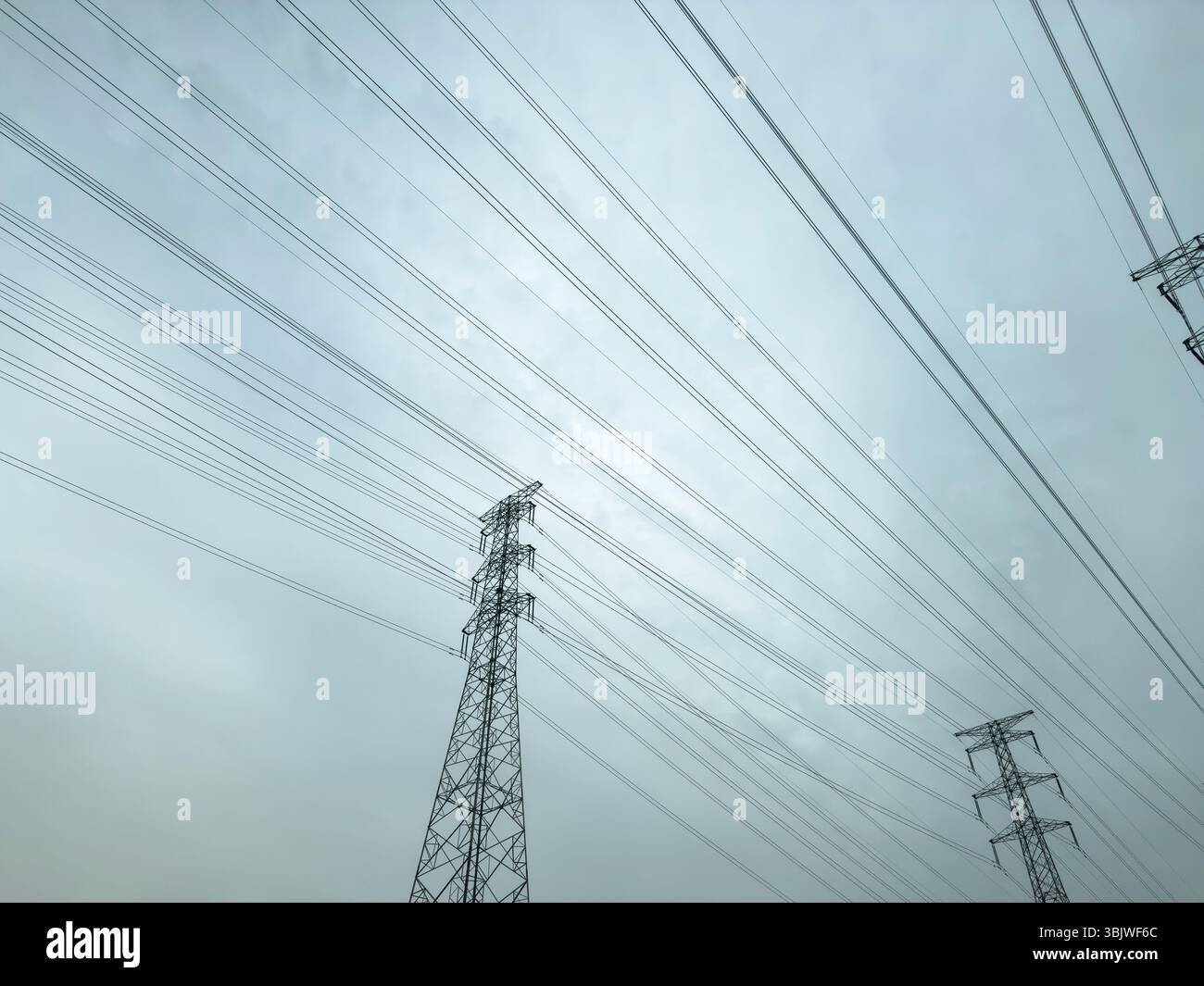 Rete di linee elettriche e torri di trasmissione in acciaio alte su sfondo nuvoloso, infrastruttura energetica Foto Stock