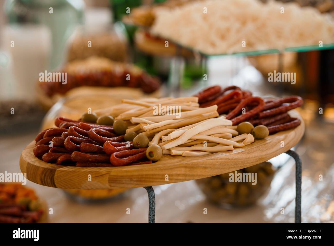 Uno shot vivace e ravvicinato mostra un tagliere di salumi ben organizzato, ricco di salumi, bastoncini di formaggio, olive e grissini croccanti, p Foto Stock