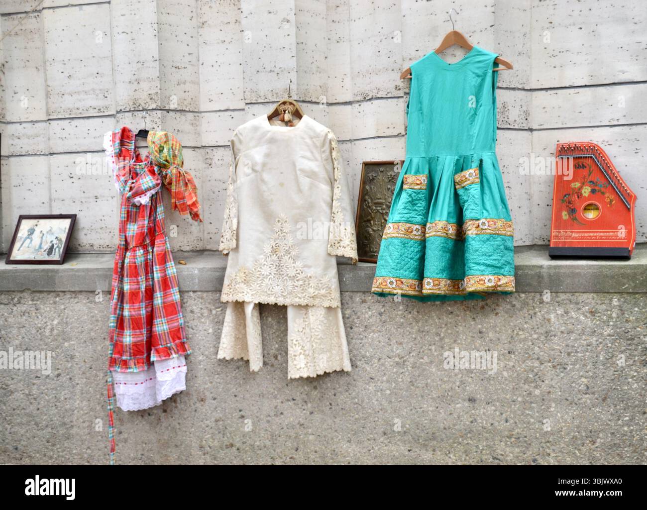Abiti prediletti di seconda mano, cappelli e altri articoli in vendita si trovano su una parete di cemento fuori da un mercato delle pulci a Parigi Foto Stock