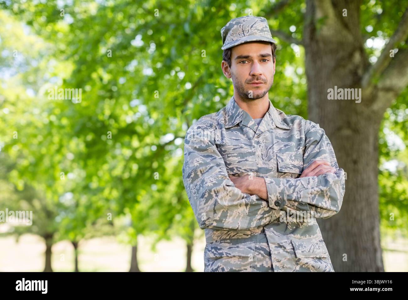 Soldato maschile in piedi in un'area boscosa con giacca mimetica e cappellino da pattuglia, copia spazio Foto Stock