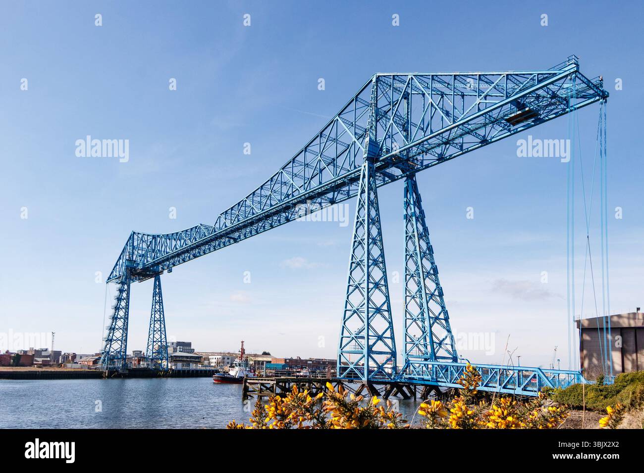 alto ponte sospeso blu middlesbrough con strutture metalliche contro un cielo azzurro e un sentiero chiuso sottostante Foto Stock