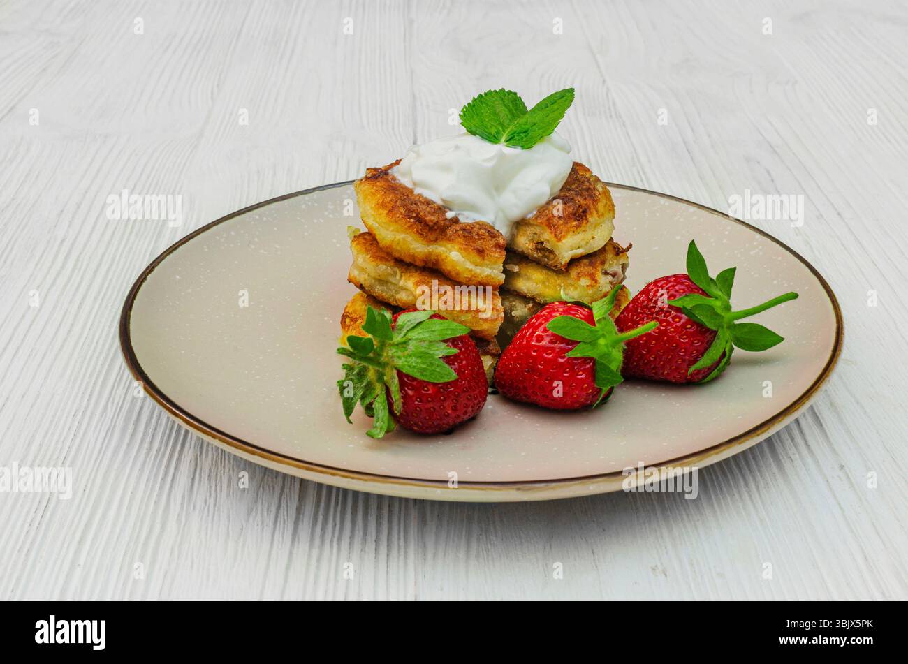 Una deliziosa pila di sciroppi fatti in casa, i tradizionali pancake al formaggio dell'Europa orientale. Le frittelle dorate sono ricoperte da un cucchiaio di sou Foto Stock