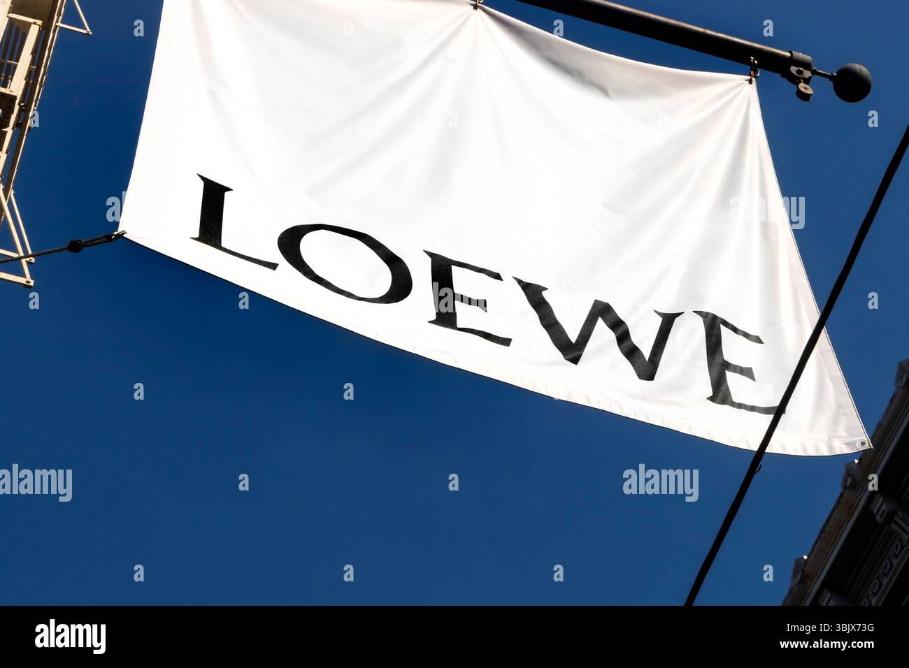 Grande bandiera bianca con logo LOEWE su un cielo blu chiaro appeso a un palo metallico in un negozio di moda a SoHo, New york Foto Stock