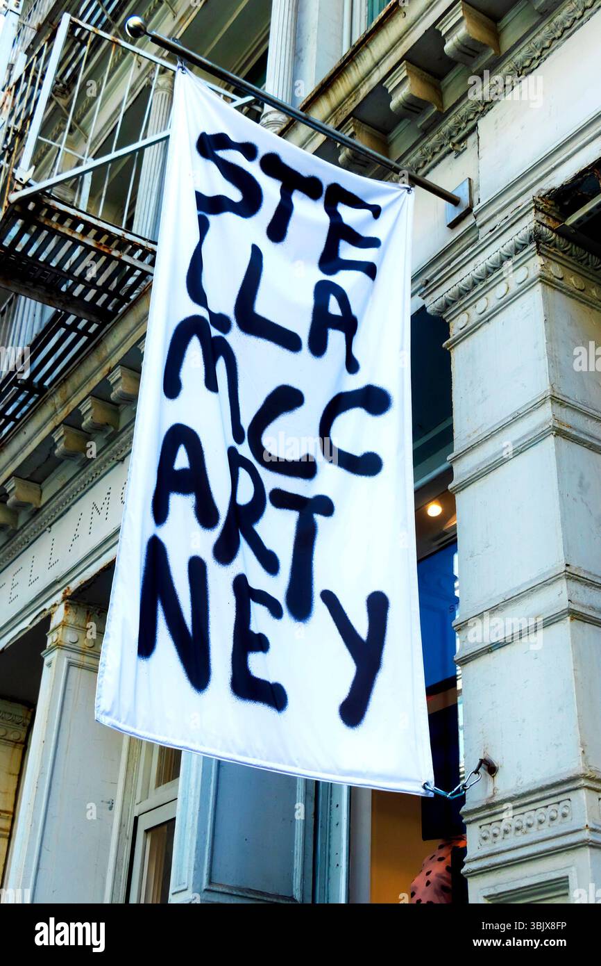 Un alto banner bianco è appeso all'esterno di un edificio con audaci lettere nere che scrivono la stilista stella mccartney Foto Stock
