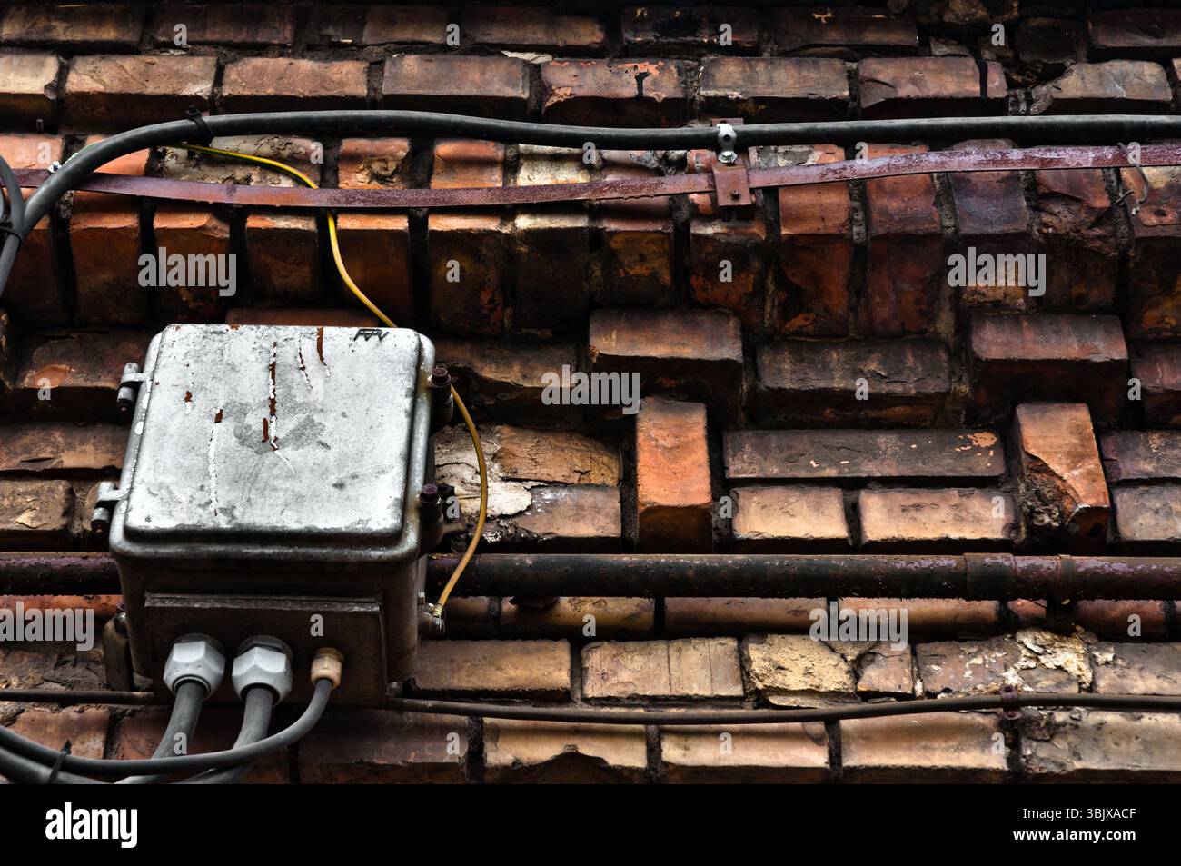 Scatola elettrica su muro abbandonato di mattoni Foto Stock