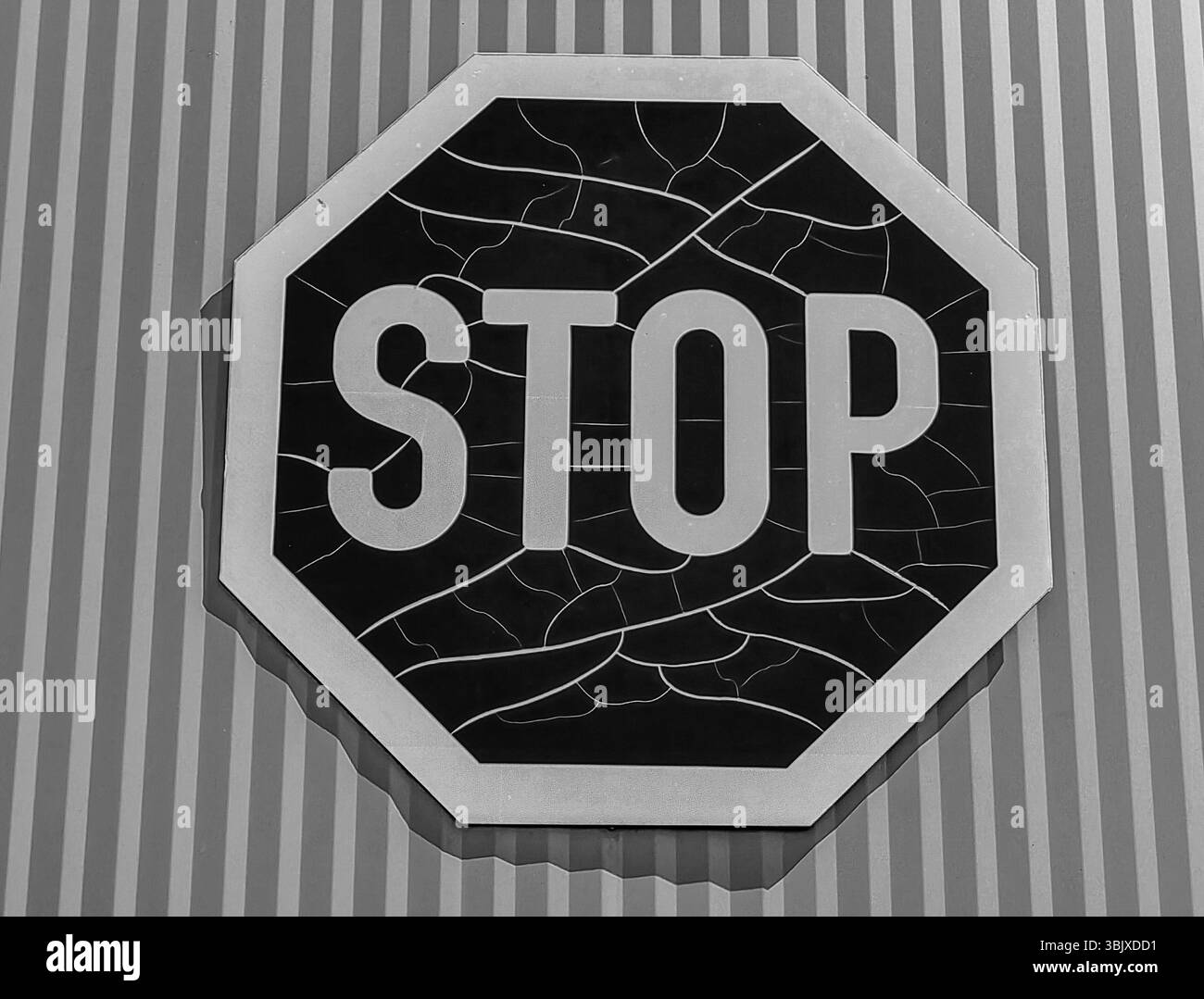 Segnale di stop resistente agli agenti atmosferici contro l'esterno della parete metallica a righe. Tonalità monocromatiche. Foto Stock