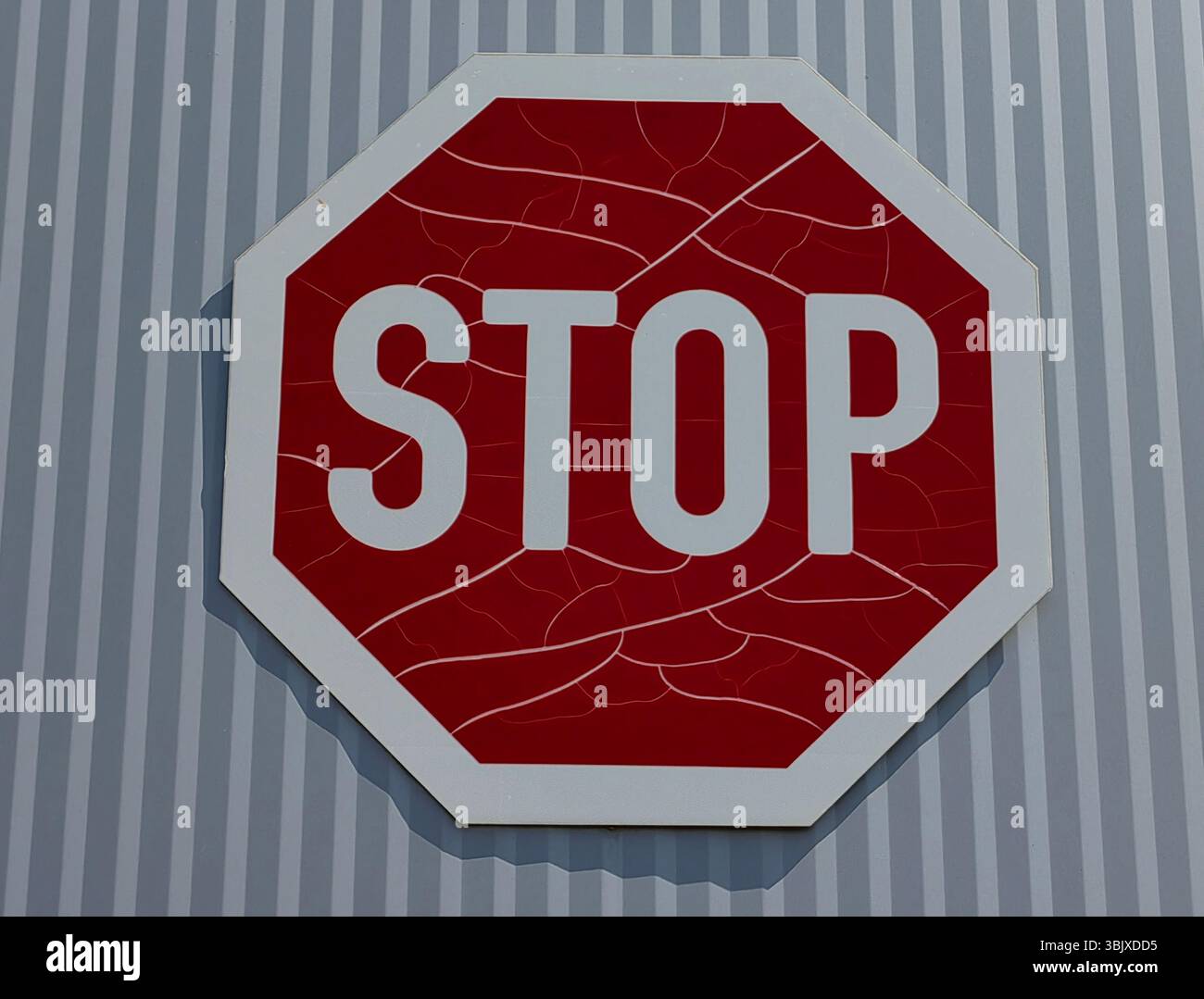 Segnale di stop resistente agli agenti atmosferici contro l'esterno della parete metallica a righe Foto Stock