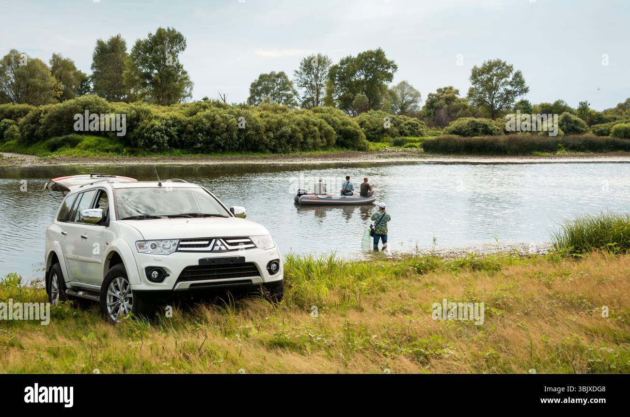 SUV bianco Mitsubishi Pajero Sport su una riva di un fiume stretto, vista di tre quarti di un'auto utilizzata dai pescatori. Regione di Chernihiv, Ucraina - luglio 30 2015. Foto Stock