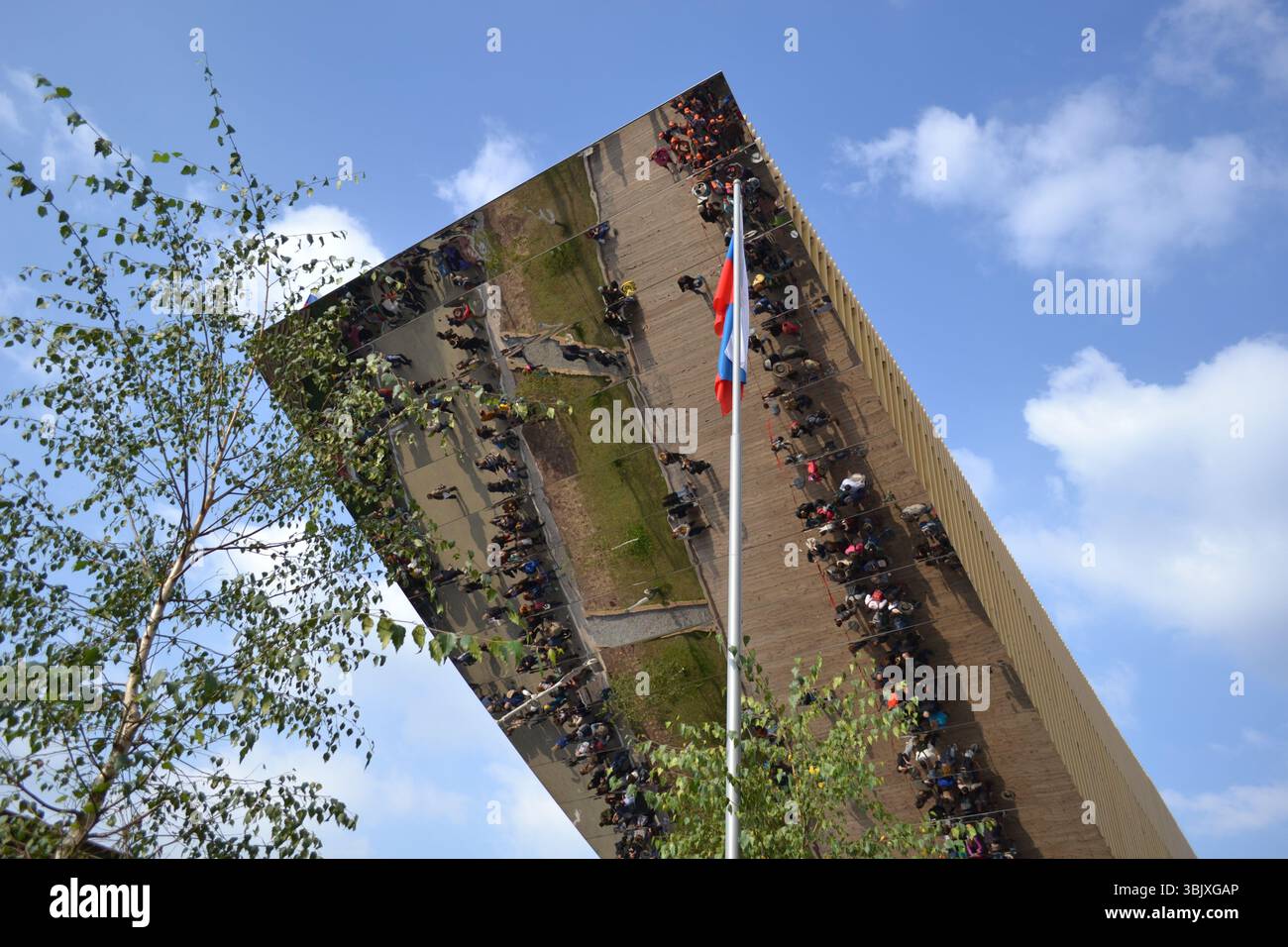 Enorme tettoia con specchio inserito e che riflette il terreno con persone in risultati distorti. Progettare la società futura. Tecnologia e ingegneria Foto Stock