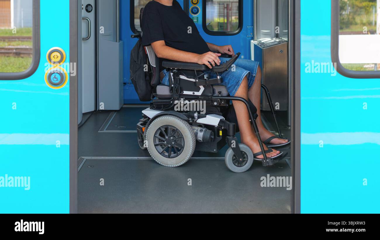 L'utente in sedia a rotelle che utilizza il treno accessibile attende alla porta di un treno, mostrando gli interni spaziosi progettati per un facile accesso. Viene visualizzato l'utente Foto Stock