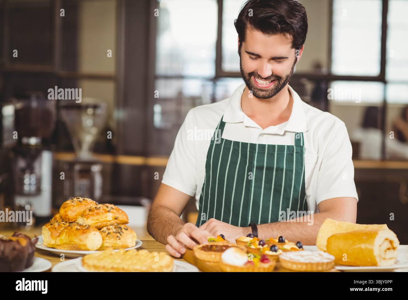Pani e crostate di frutta appoggiate su un banco di legno sotto una luce calda vicino ai pannelli delle finestre di vetro Foto Stock
