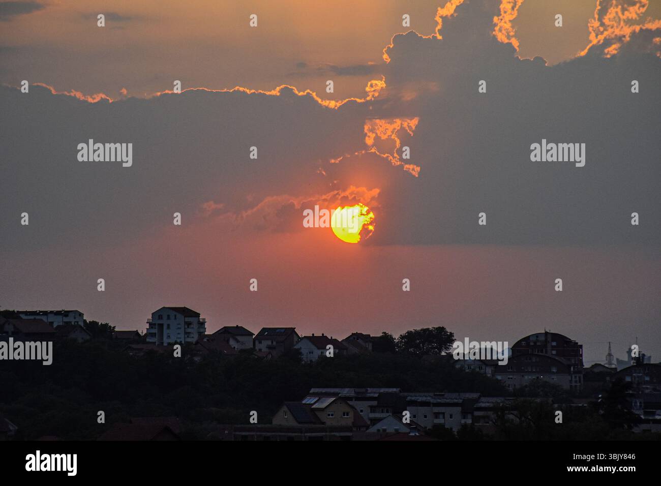 Panorama urbano al tramonto con sole dorato e cielo serale colorato Foto Stock