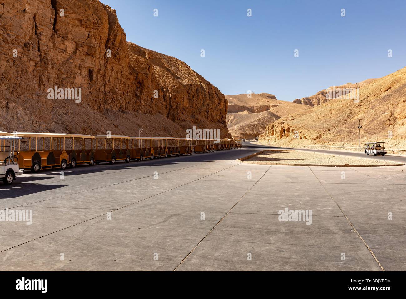 Una lunga fila di carrelli passeggeri è parcheggiata nella Valle dei Re, in attesa di trasportare i turisti verso le varie tombe. Foto Stock