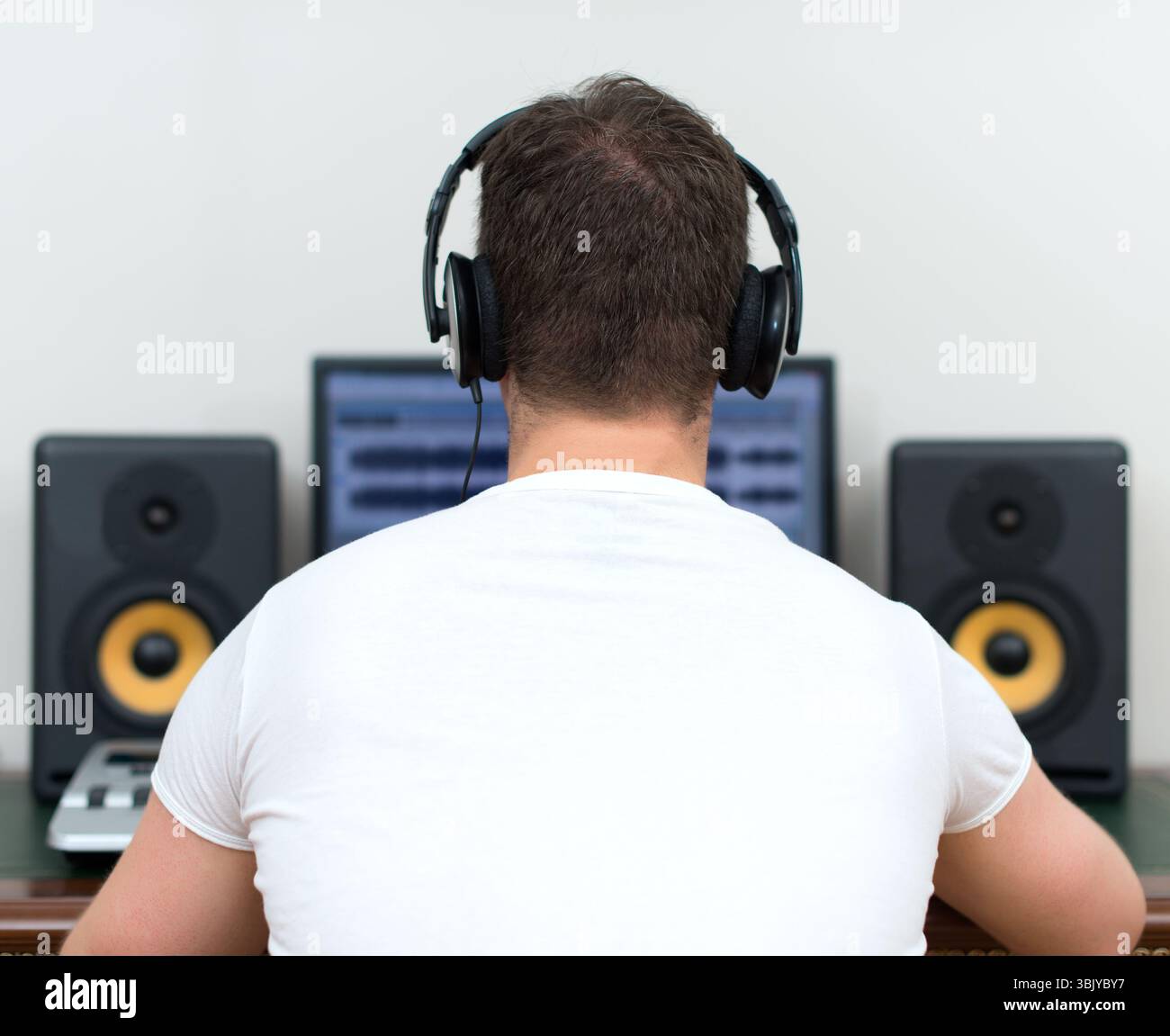 Maschio produttore audio in studio di registrazione. Vista posteriore. Spazio per il testo. Foto Stock