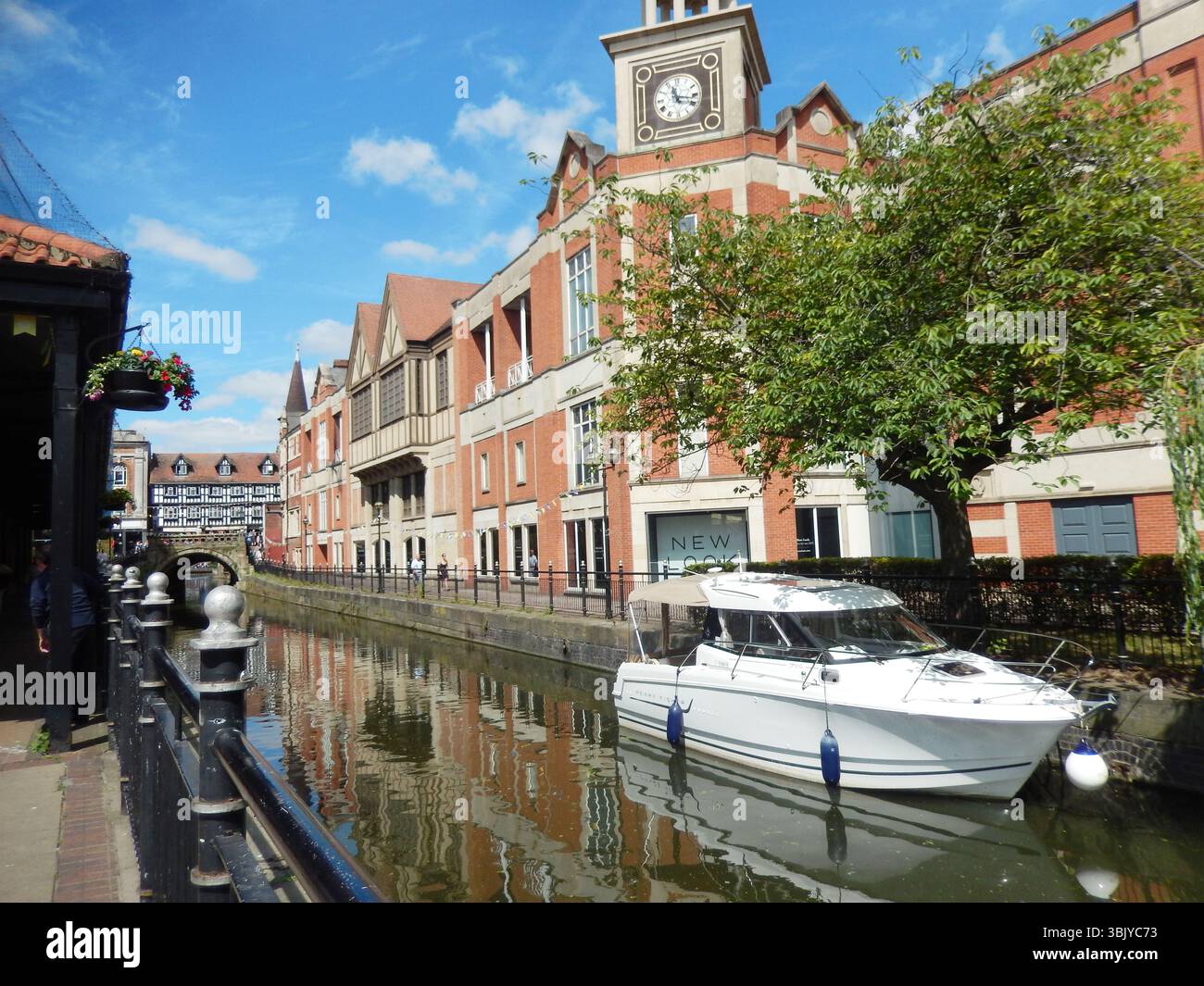 Affascinante scenario del canale con edifici della città e barca attraccata sotto il cielo azzurro. Lincoln, Inghilterra Foto Stock