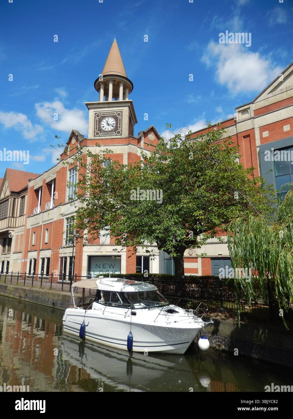 Affascinante scenario del canale con edifici della città e barca attraccata sotto il cielo azzurro. Lincoln, Inghilterra Foto Stock