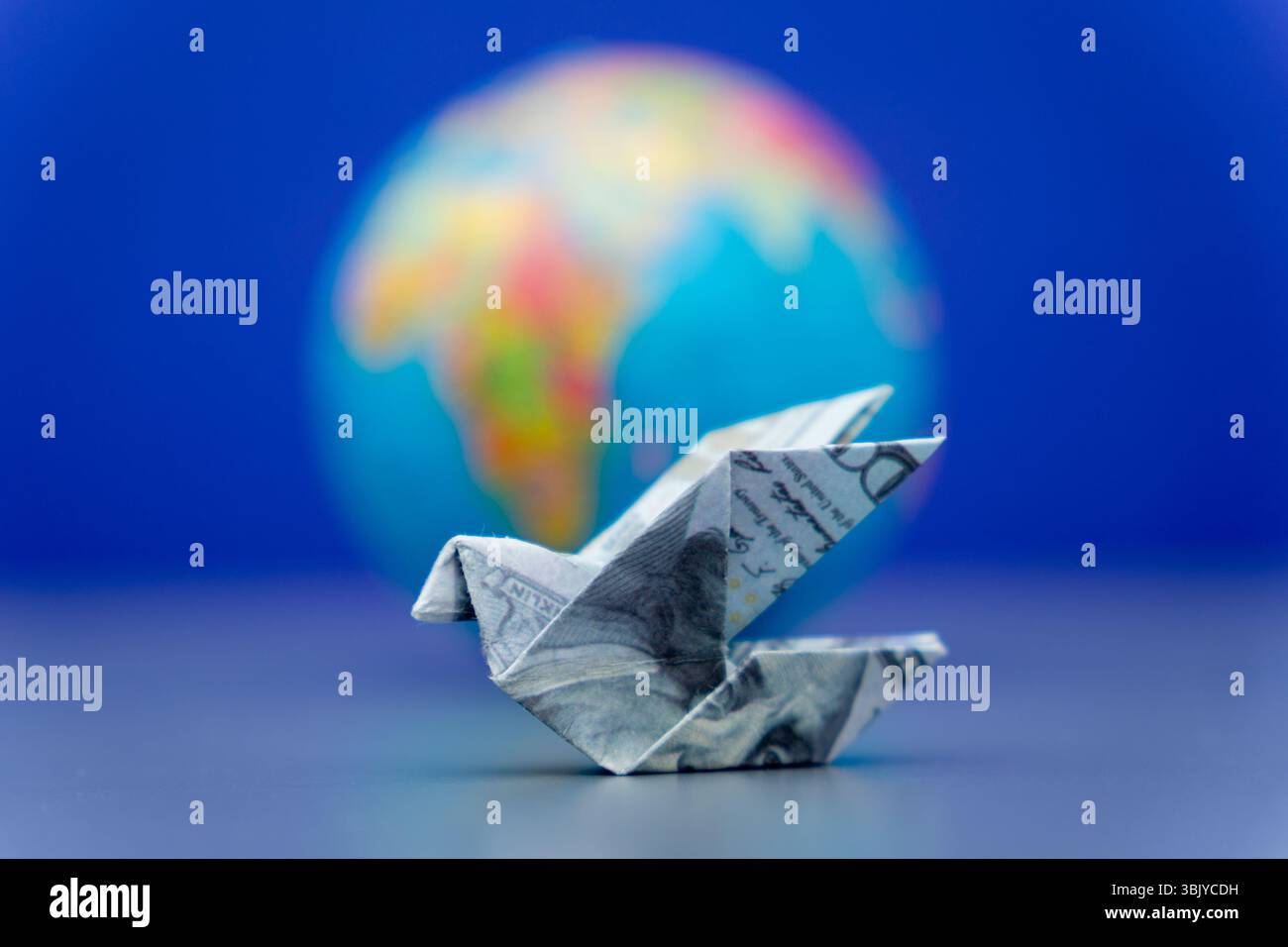 Un uccello di origami è caduto da una banconota da un dollaro americano e da un globo. Concetto di trasferimenti finanziari internazionali, rimesse e movimento monetario globale. Foto Stock