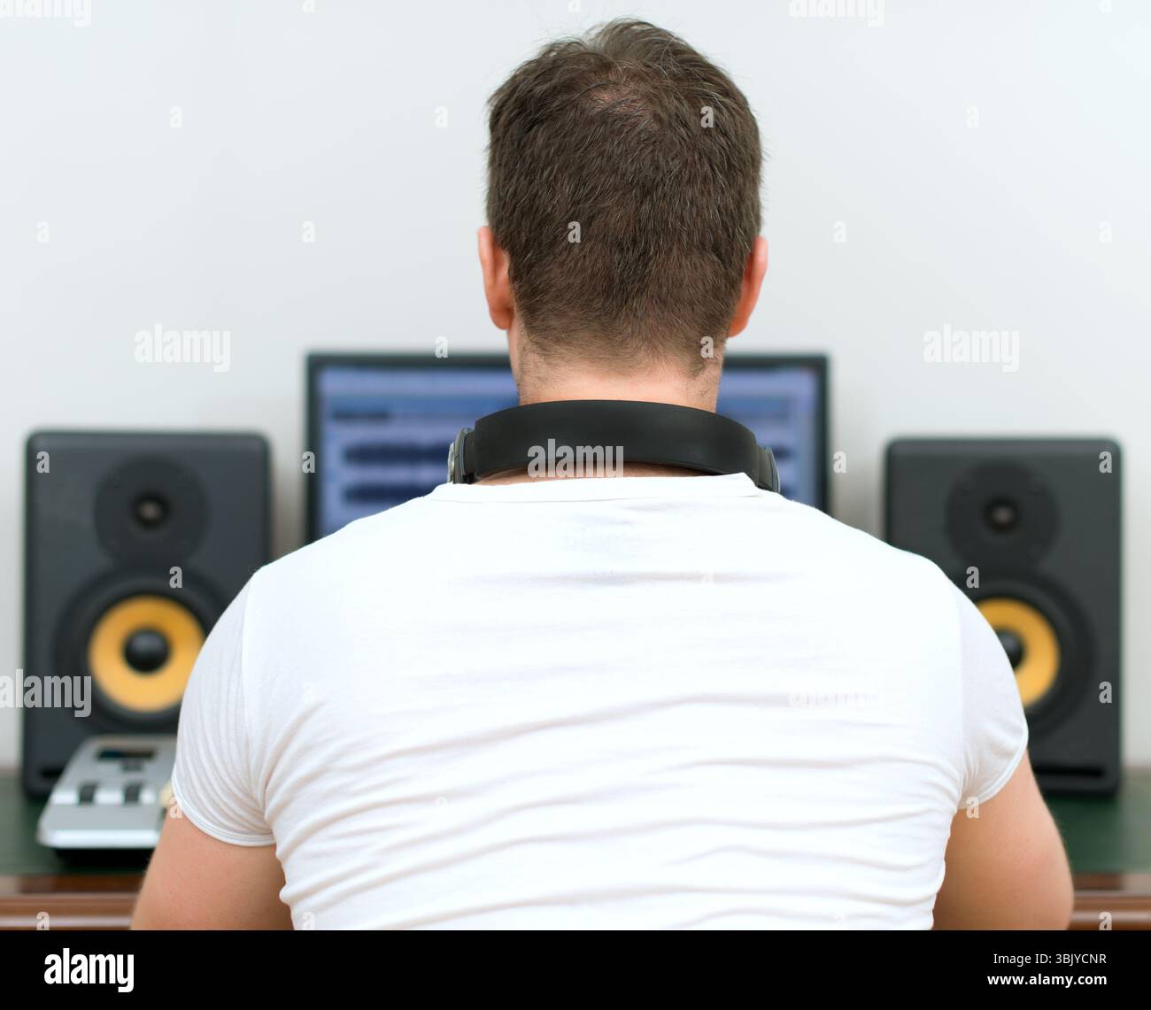 Maschio produttore audio in studio di registrazione. Vista posteriore. Spazio per il testo. Foto Stock