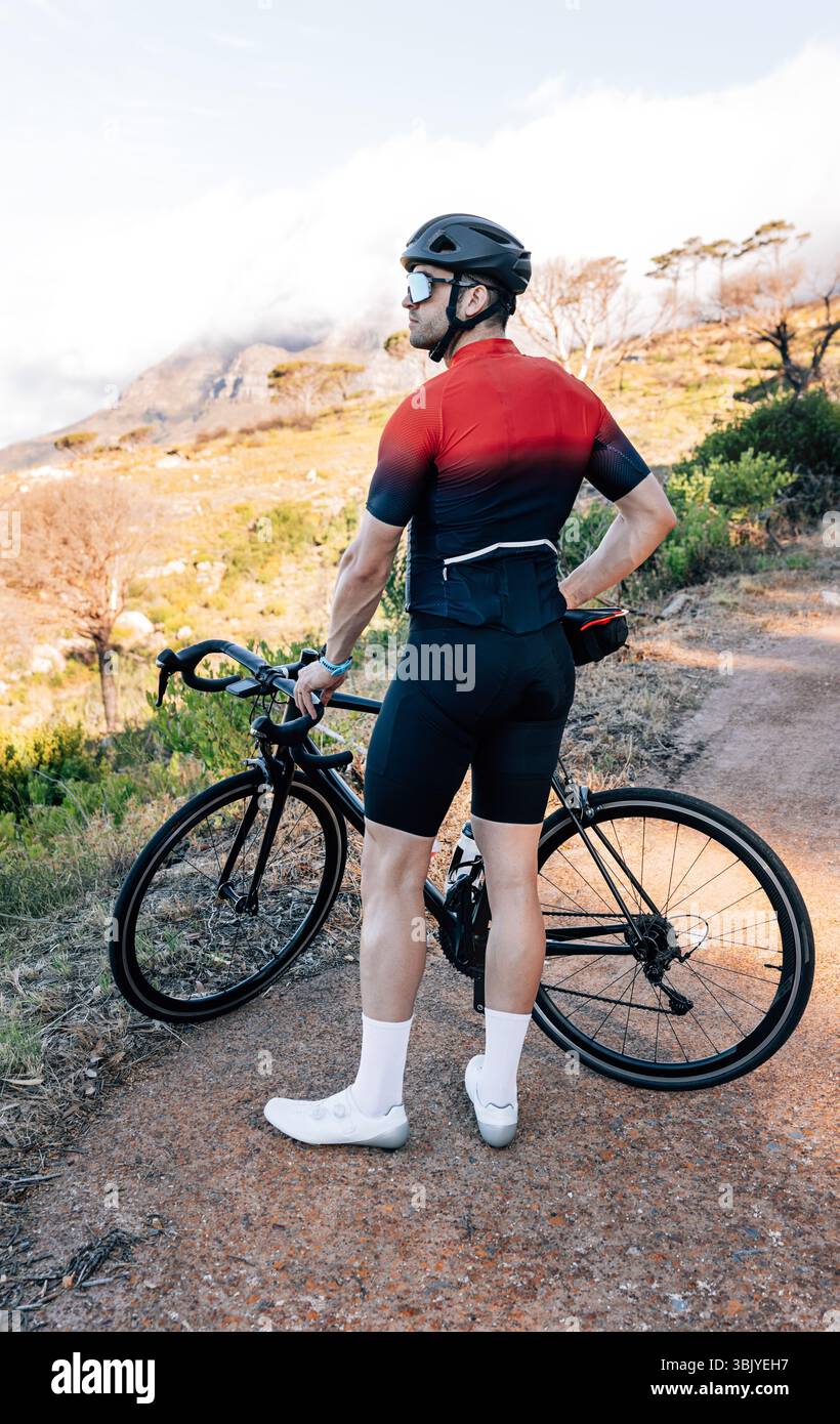 Vista posteriore di un ciclista godendo la vista nel terreno selvaggio Foto Stock