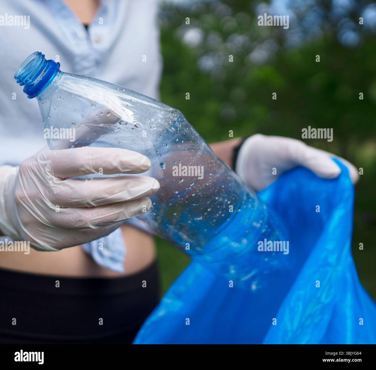 Volontario che tiene bottiglia di plastica. Concetto di inquinamento ambientale. Foto Stock