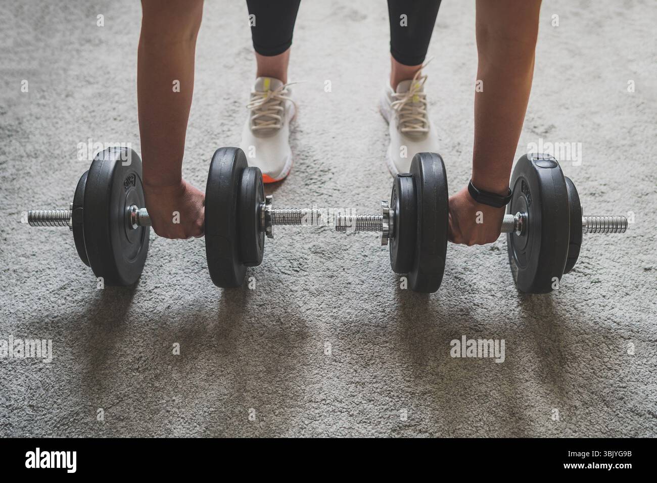 La donna si sta preparando a lavorare con i manubri. Concetto di allenamento domestico per il fitness. Foto Stock