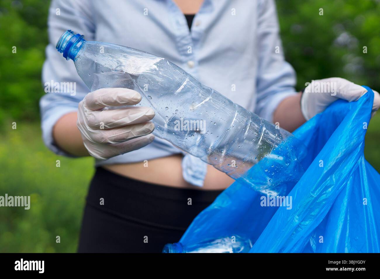 Volontario che tiene bottiglia di plastica. Concetto di inquinamento ambientale. Foto Stock