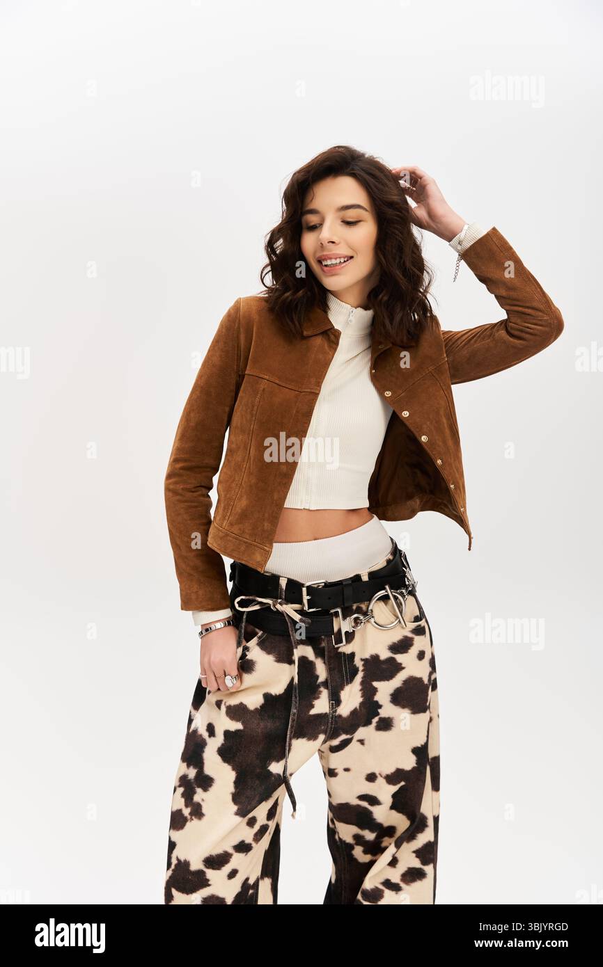 Una giovane donna chic modella con fiducia un outfit alla moda con pantaloni con stampa mucca in uno studio. Foto Stock