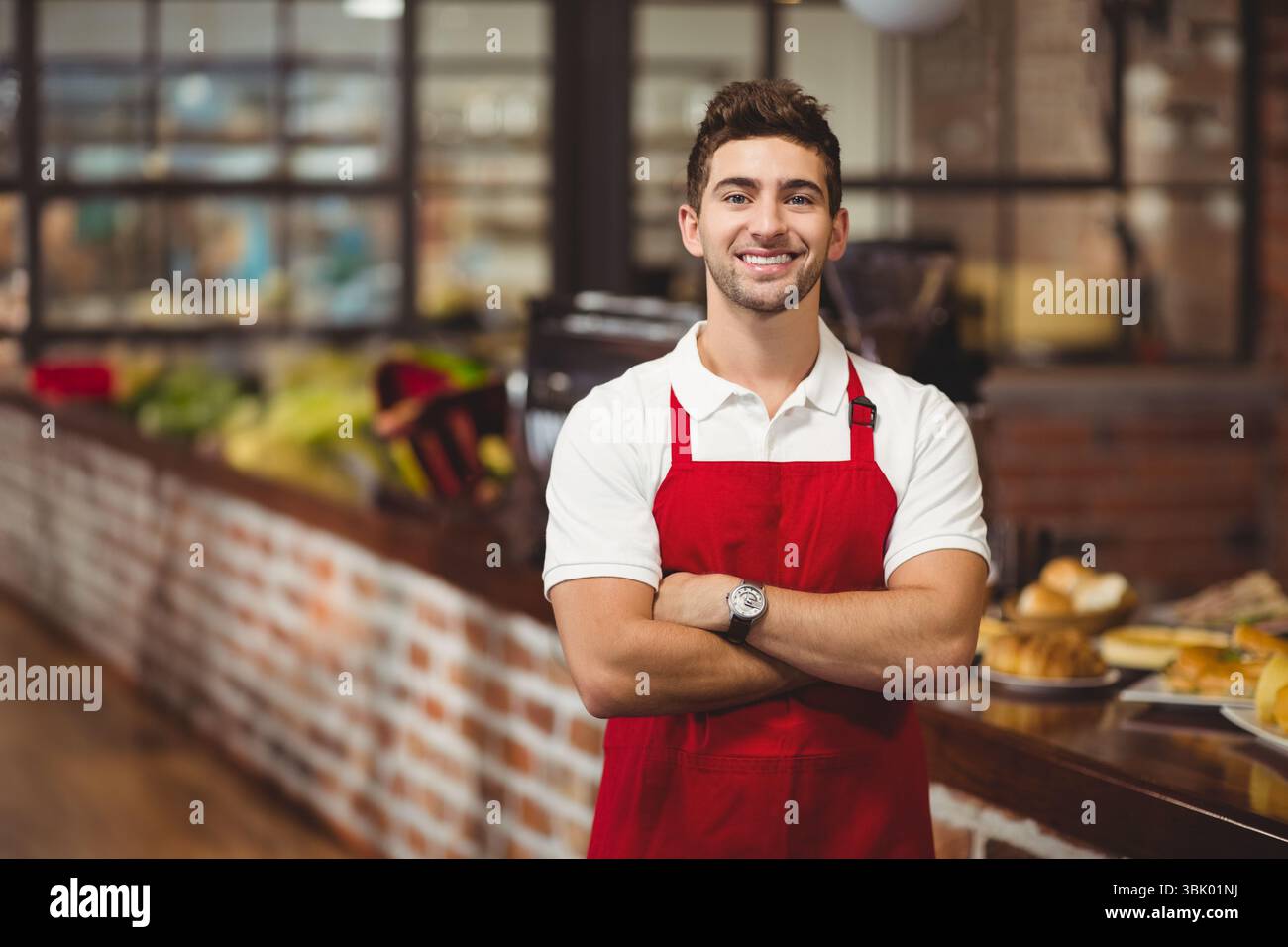 Bancone in mattoni con croissant e pane accanto alle macchine per il caffè a vapore, sotto luci calde Foto Stock